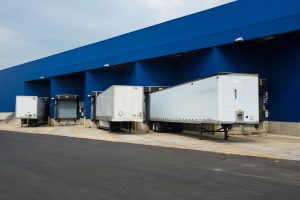 A row of tractor trailers lined up at a loading dock to illustrate loading dock restraints